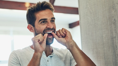 Young man pressing bottoms of sore front teeth with thumbs