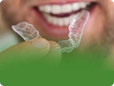 Smiling bearded man holding clear Invisalign retainer