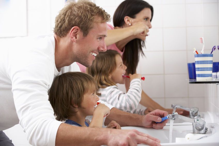 Young parents teaching oral care routine to children in Stoney Creek washroom