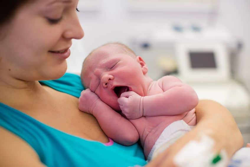 Young mother cradling yawning newborn in Stoney Creek hospital