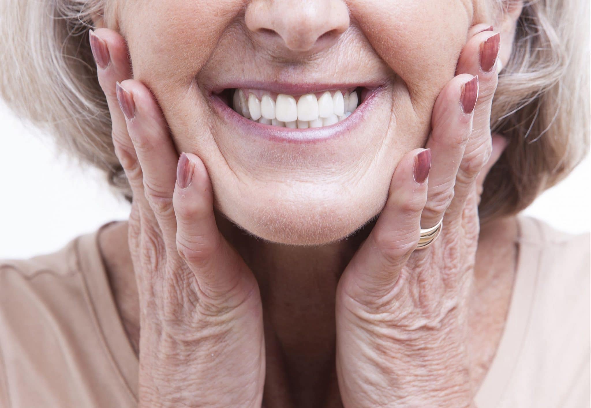 Elderly woman holding her face and showing off dentures