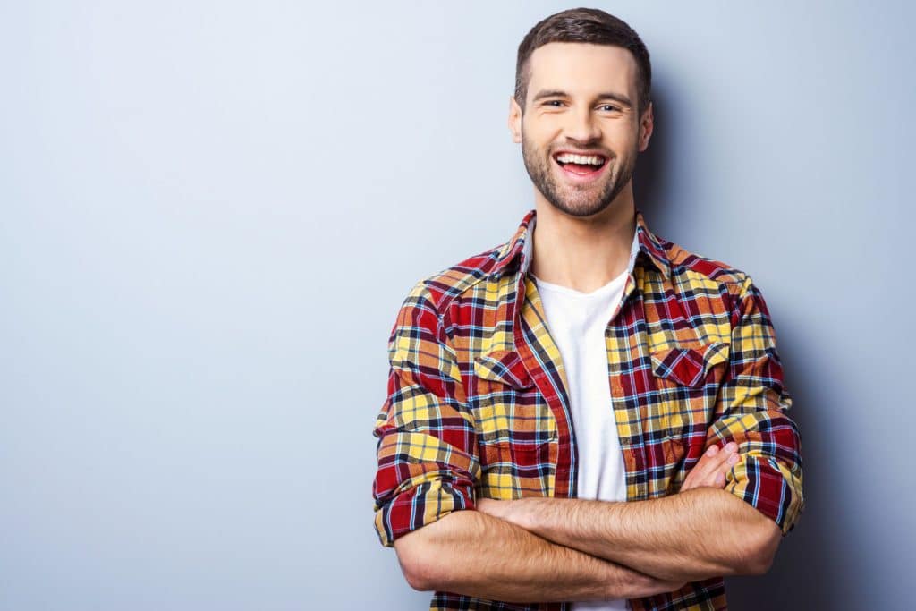 Happy young man in red flannel smiling after cosmetic dentistry