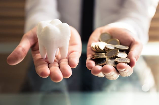 Dental insurance salesman holding model tooth in one hands, coins in the other