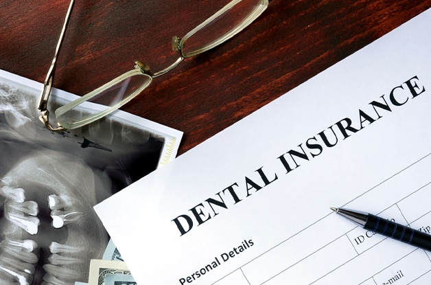 Dental office desk with dental insurance document, pen, glasses, and x-ray