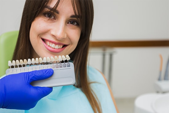 a woman smiling while showing her the dental implants