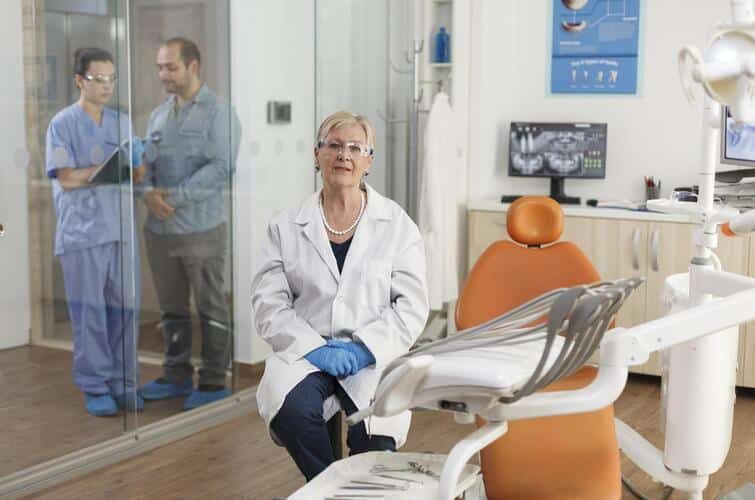 Portrait of stomatologist doctor looking into camera while waiting for patient during stomatology consultation in medical dental office. Orthodontist senior woman working at dentistry treatment