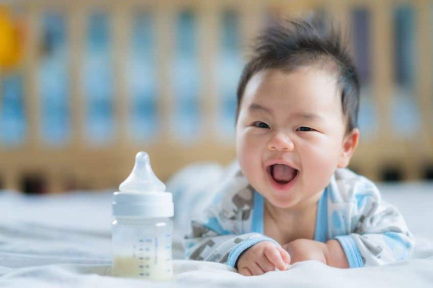 Cute smiling infant in crib with bottle