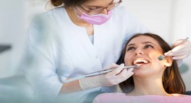 Dental hygienist cleaning young woman's teeth before wisdom teeth removal