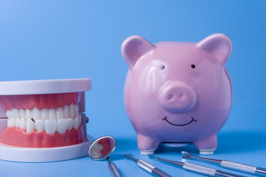 Piggy Bank on a blue background and dental instruments. The concept of saving money for the manufacture of dental implants and treatment.