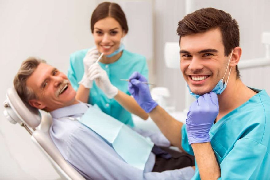Young dentist and his assistant treating elderly man