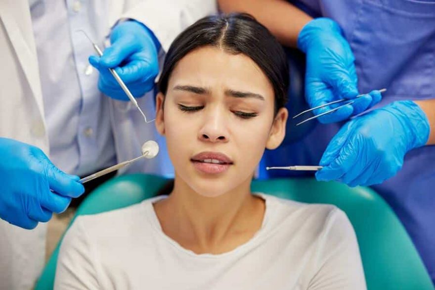 a young woman experiencing anxiety while having a dental procedure performed on her.