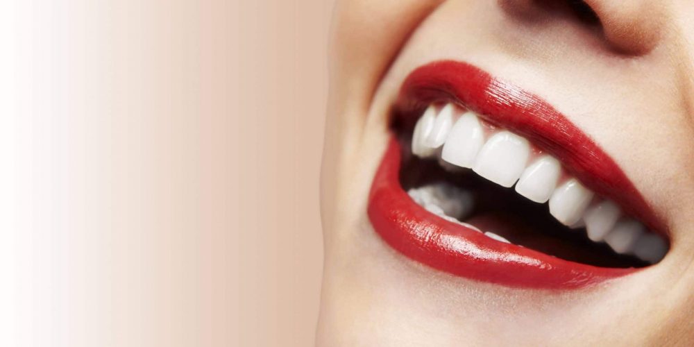 Young woman with ruby lipstick smiling after teeth whitening