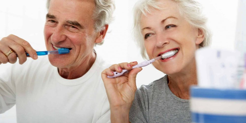 Healthy elderly couple brushing teeth together in Stoney Creek bathroom