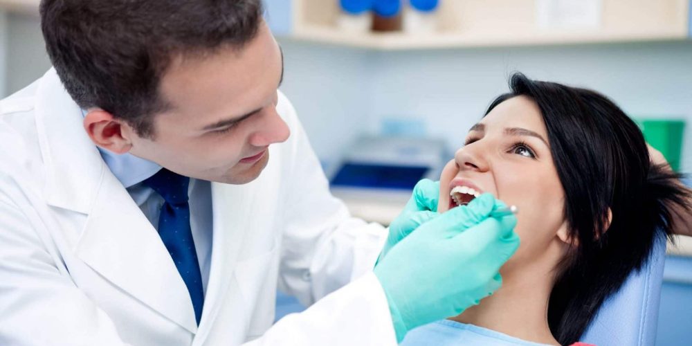 Well-dressed Stoney Creek dentist checking patient's teeth for cavities