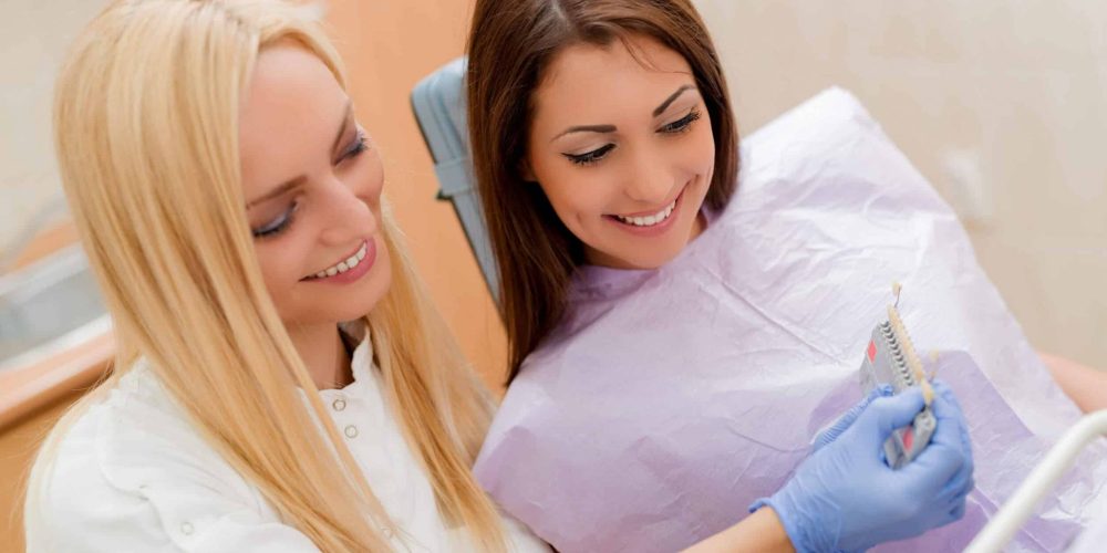 Young blond dentist showing custom crowns to patient in Stoney Creek dental clinic